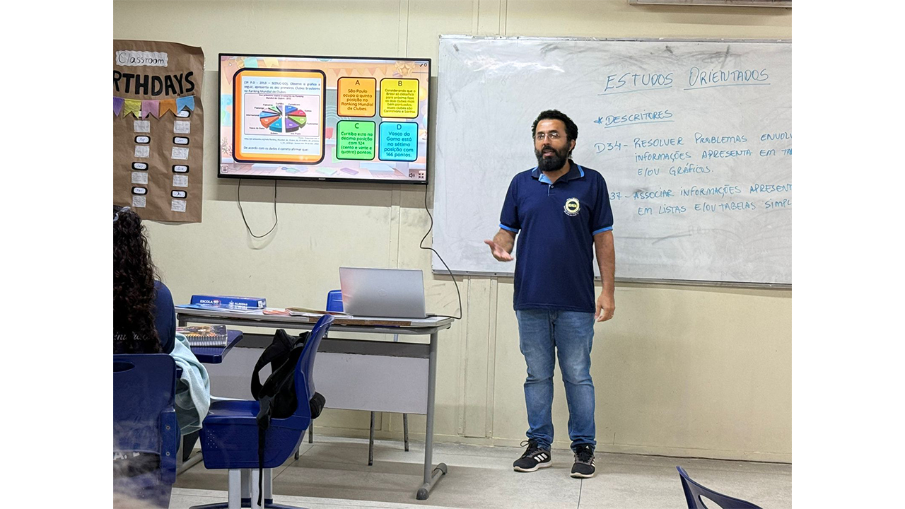 Angel Barbosa Delfino, professor de eletivas de jogos matemáticos da Escola Estadual Professora Edleuza Oliveira da Silva, explicando como funciona o Projeto Professor Mentor, em São Miguel dos Campos (AL). Foto: Jamilla Salviano